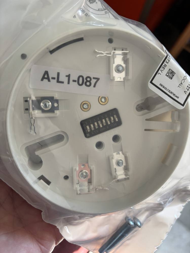 Addressable detector base with its dipswitches set and an address label reading A-L1-087 applied to the base.
