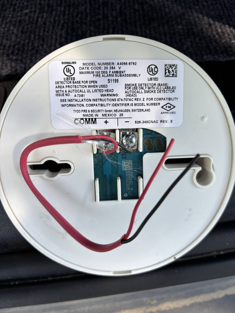 Detector base with a red and black fire-rated whip cable landed on the COMM plus and minus terminals.