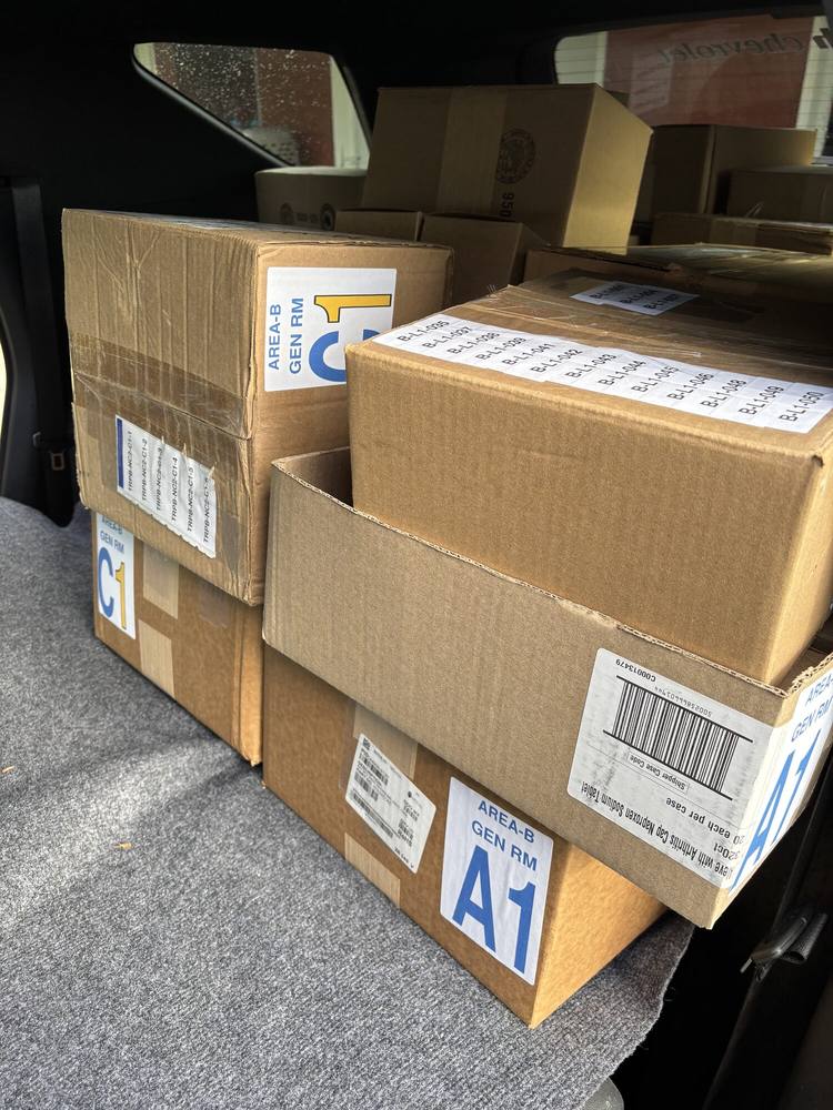 Stacked cartons carrying large blue area placards reading AREA-B GEN RM A1 and C1.