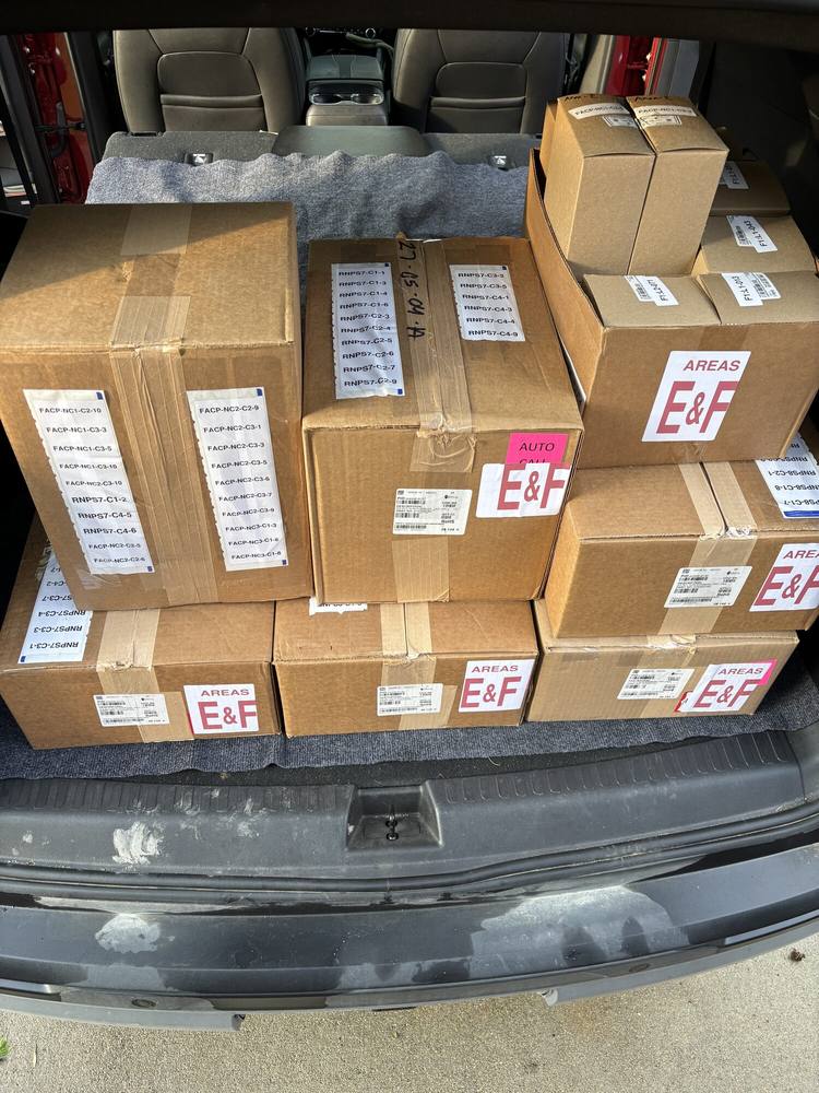 A vehicle loaded with labeled cartons, color-coded with placards reading AREAS E and F.
